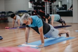 Over 60s male doing push-ups in an exercise class